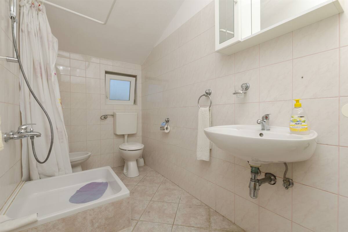 A bathroom with a bathtub, toilet, sink, and a window above the toilet.