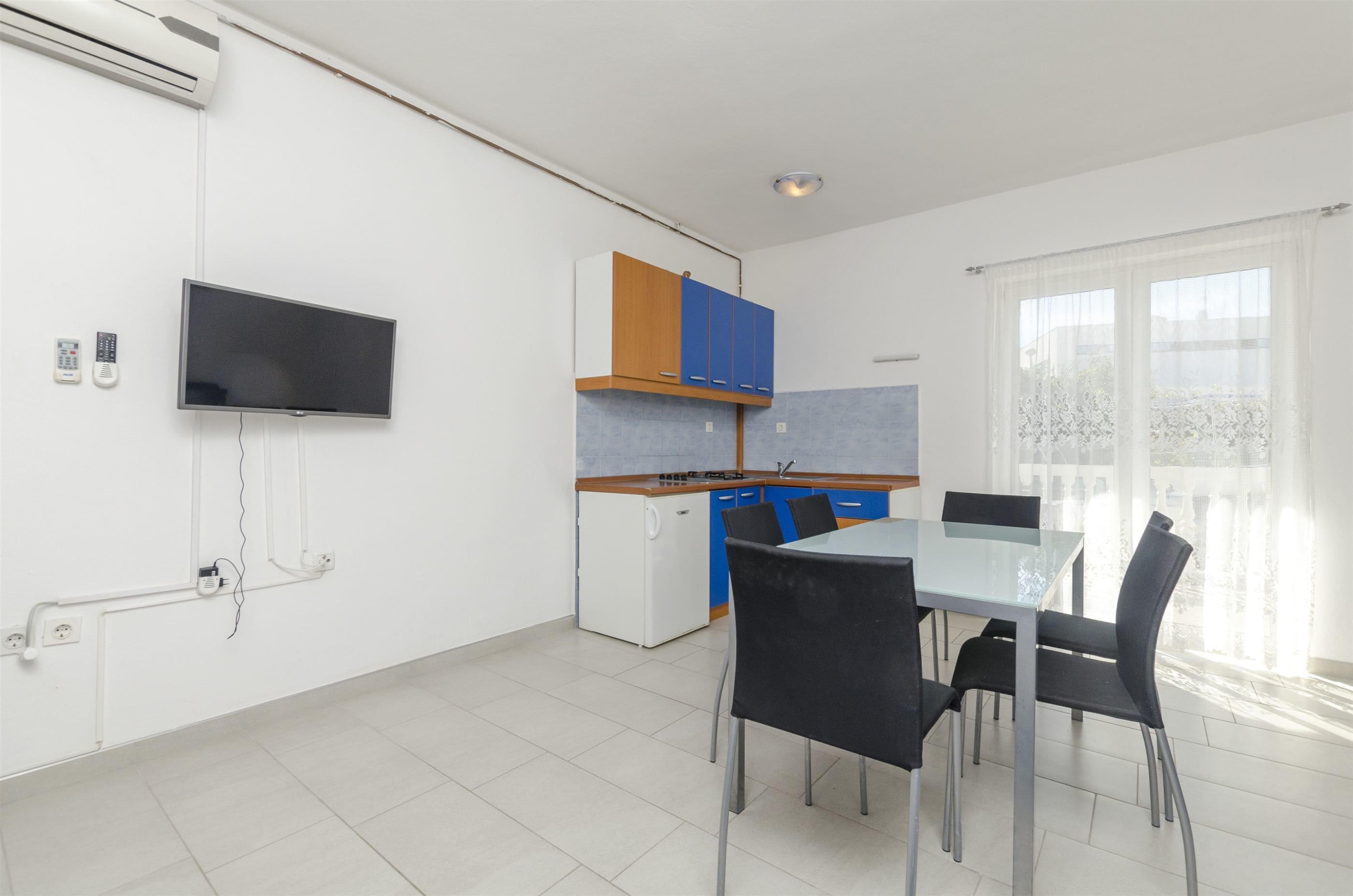A modern kitchen with a built-in oven, a small refrigerator, and a dining area with a table and chairs.