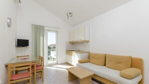 Un espace de vie compact comprenant un coin cuisine, un canapé, une table à manger avec des chaises et un téléviseur.