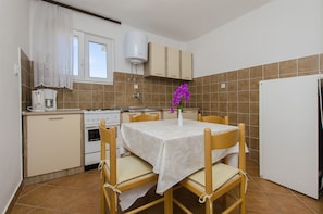 Una cocina compacta con una mesa de comedor, sillas, un refrigerador, una estufa y un calentador de agua.