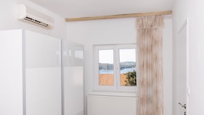 Een kamer met een witte radiator, een raam met uitzicht op een gebouw met rode dakpannen en een witte deur.