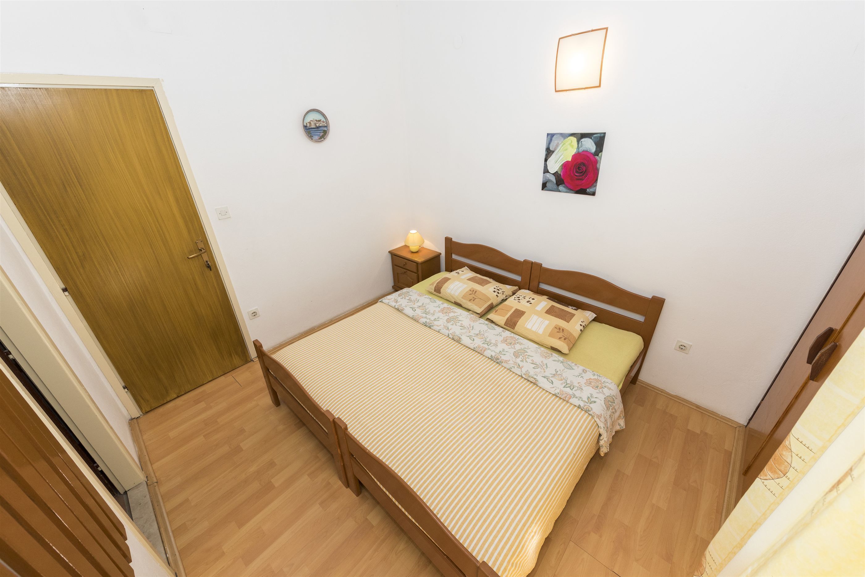 Une chambre à coucher avec un lit en bois, une table de chevet avec une lampe, une horloge murale et un tableau encadré.