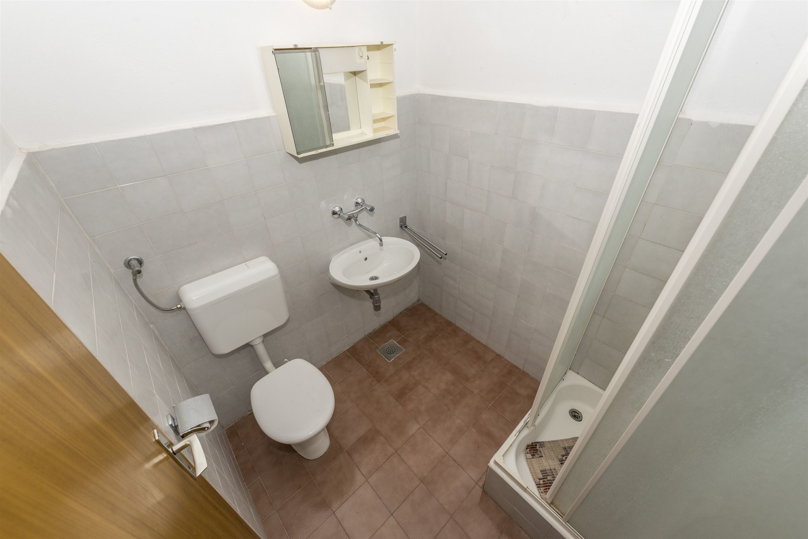 A small bathroom with a toilet, sink, and shower.