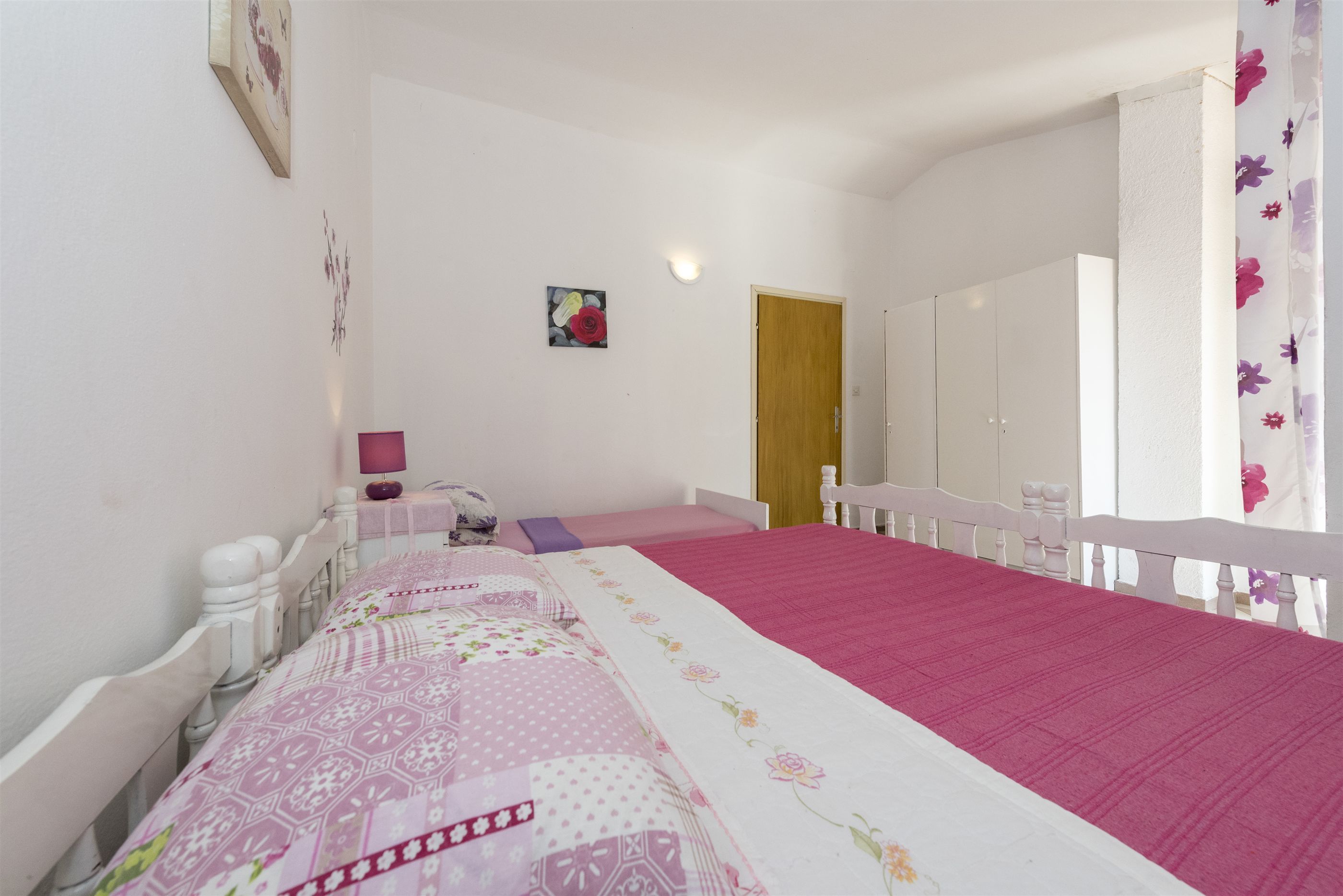 Une chambre à coucher avec un grand lit, une porte en bois et une armoire blanche.