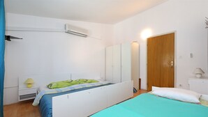 Quarto com cama, guarda-roupa, mesa de cabeceira, luminária e ar condicionado.