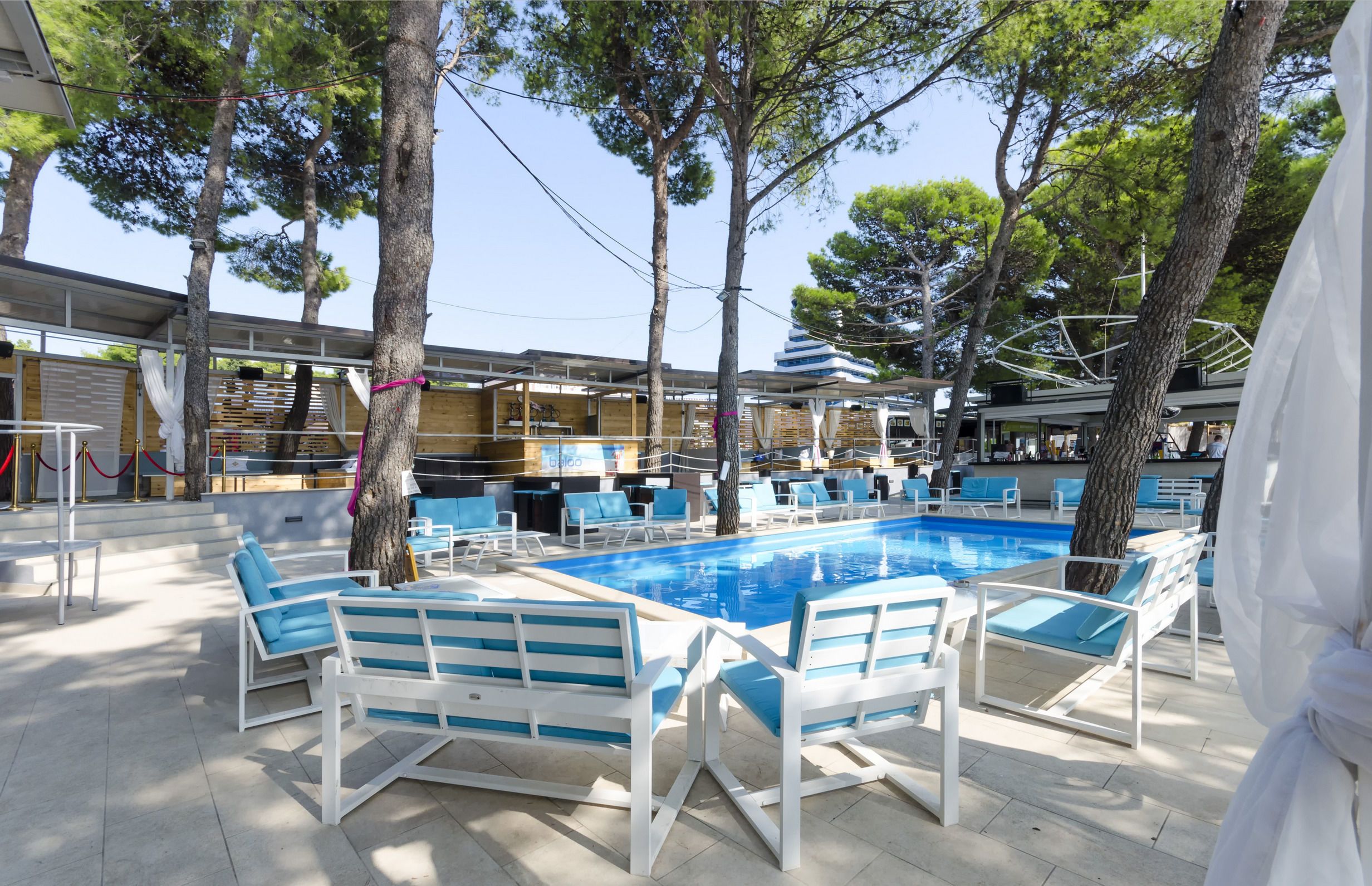 An outdoor swimming pool area with lounge chairs and a covered seating area.