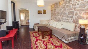 Una sala de estar con pared de piedra, un sofá, una mesa roja y una chimenea.