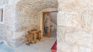 Una habitación con paredes de piedra, una mesa y sillas de madera, y un banco rojo.