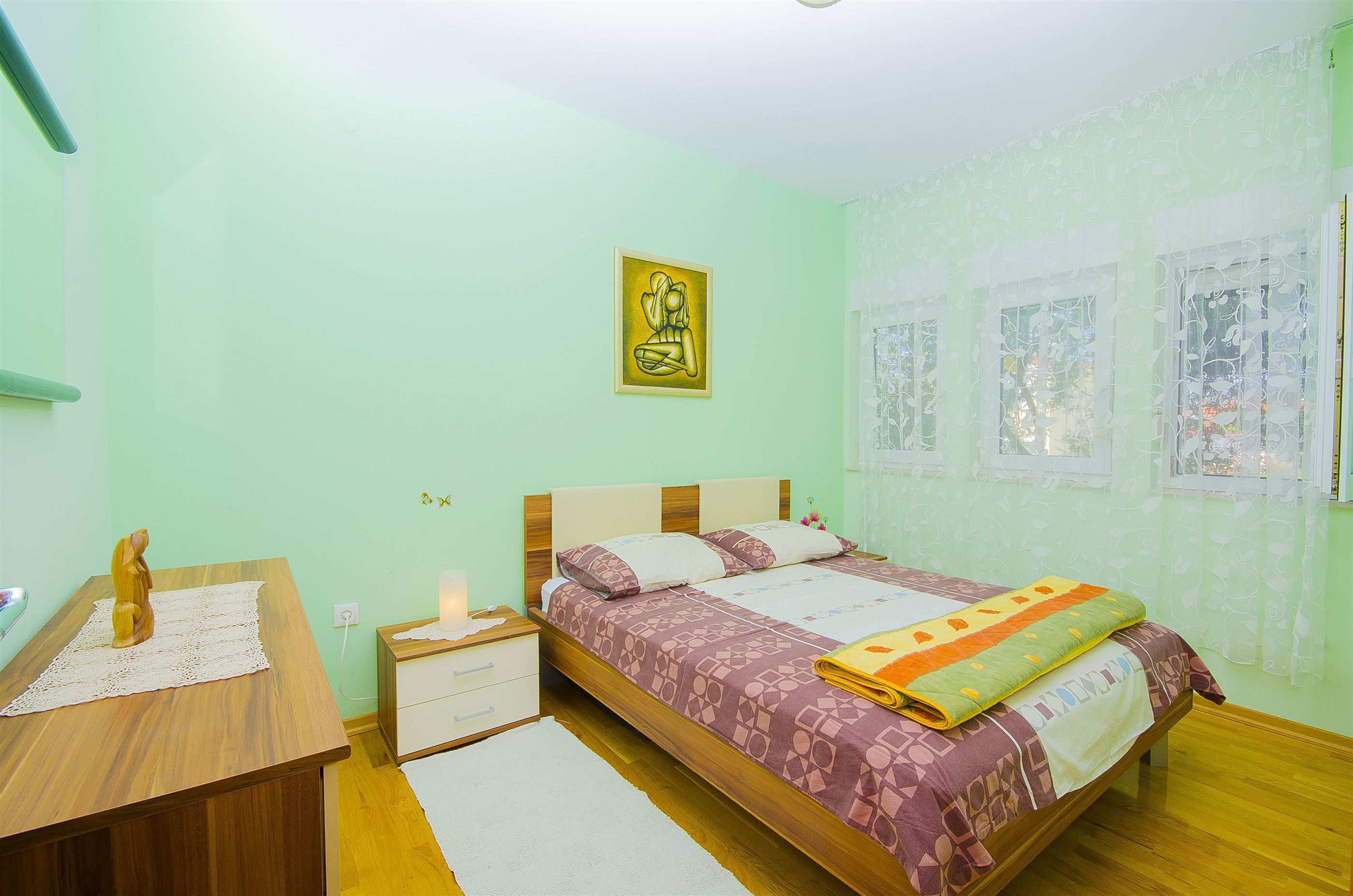 A bedroom with a bed, bedside table, and a small desk with a chair.