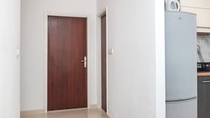 Un pasillo con una puerta de madera y una pared blanca.