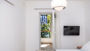 Un dormitorio con cama, televisor montado en la pared y puerta al balcón.