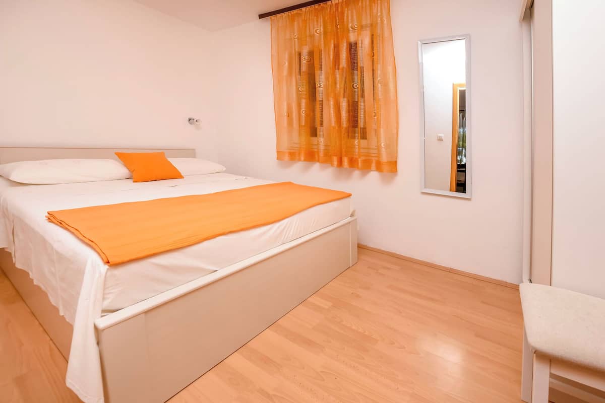 A bedroom with a bed, a chair, and a mirror.