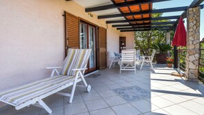 Et overdækket udendørs område med loungestole med striber og en rød parasol.