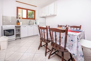 Een keuken met witte kastjes, een fornuis en een eettafel met stoelen.