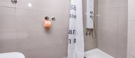 Une salle de bain avec des toilettes, une douche et une baignoire.