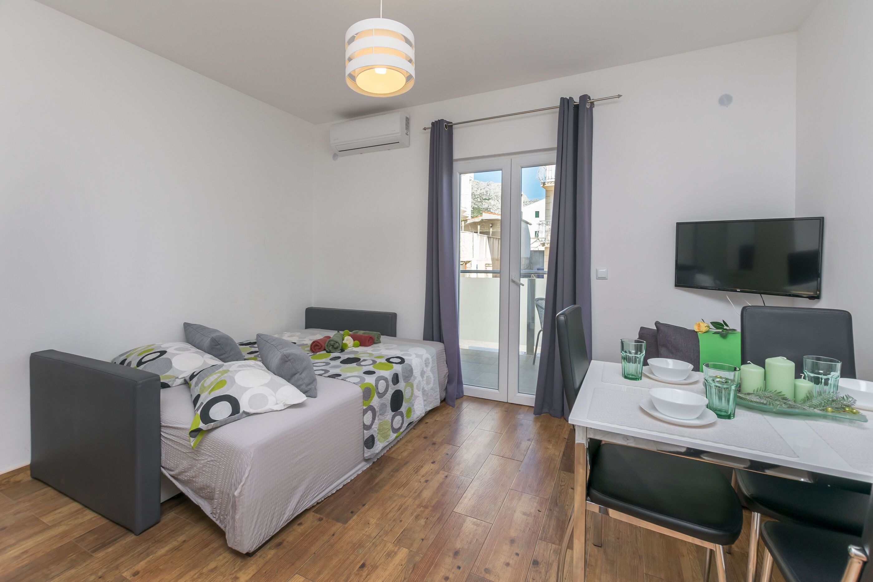 A modern room with a bed, a dining table, and a TV.
