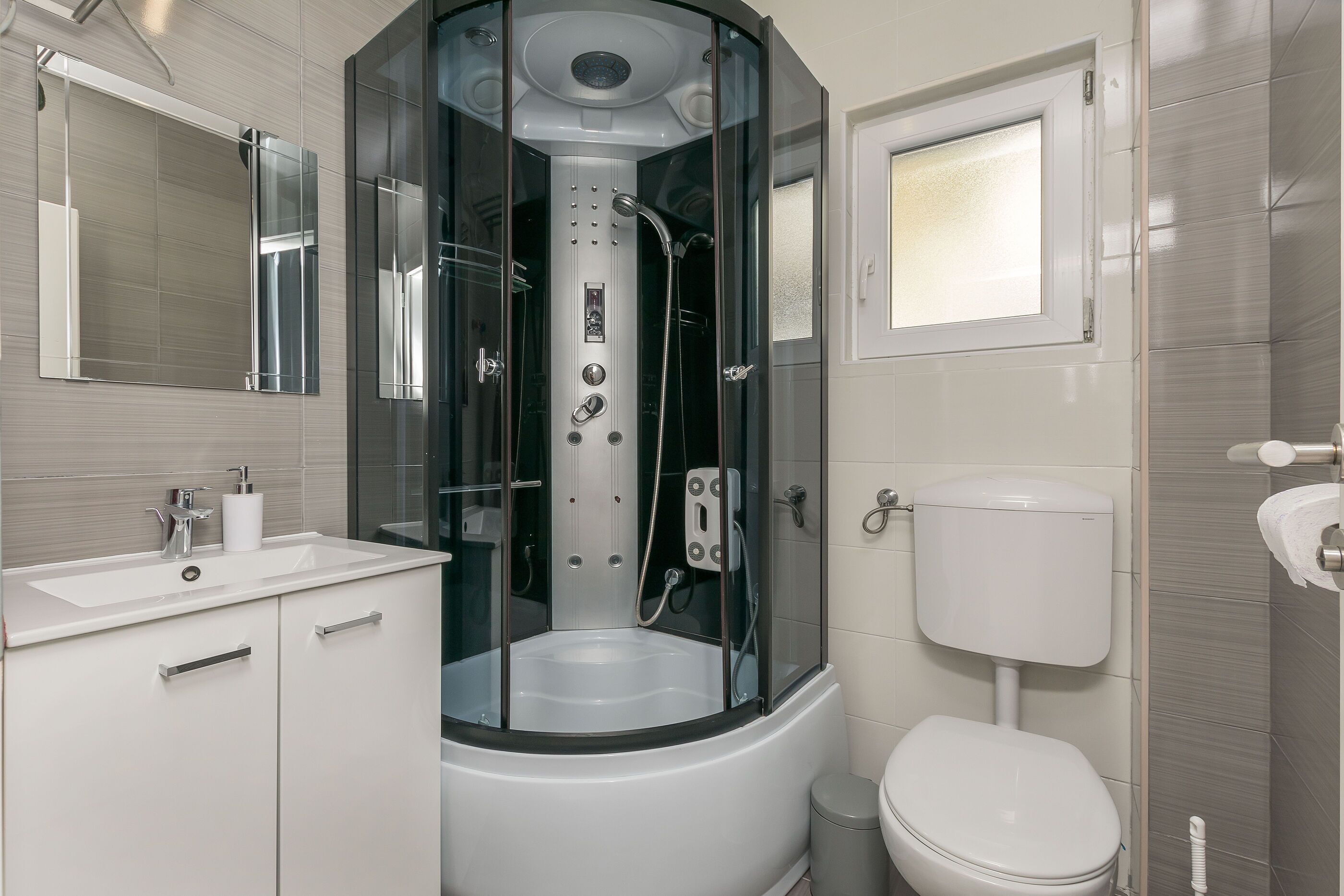A modern bathroom with a glass-enclosed shower, a white sink, and a toilet.
