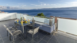 A terrace with a table set for dining, overlooking a coastal view. - Apartments Lorenzo (Lokva Rogoznica)