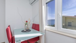 A modern dining area with a glass table, red chairs, and a vase with flowers. - Apartments Lorenzo (Lokva Rogoznica)