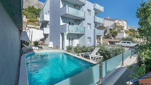 A modern building with a swimming pool, balconies, and a clear view of a mountain. - Apartments Lorenzo (Lokva Rogoznica)