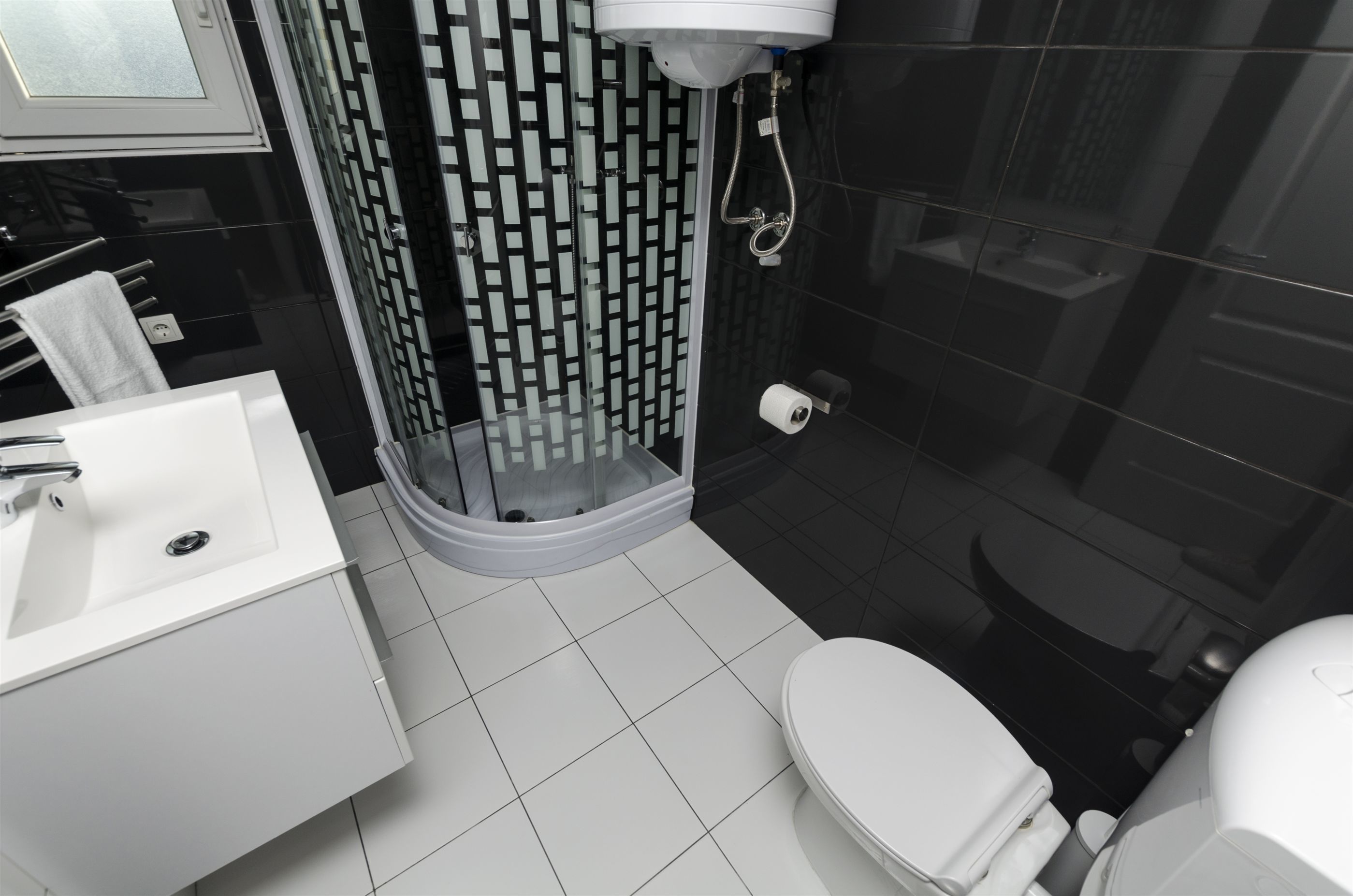 A modern bathroom with a white sink, toilet, and shower.