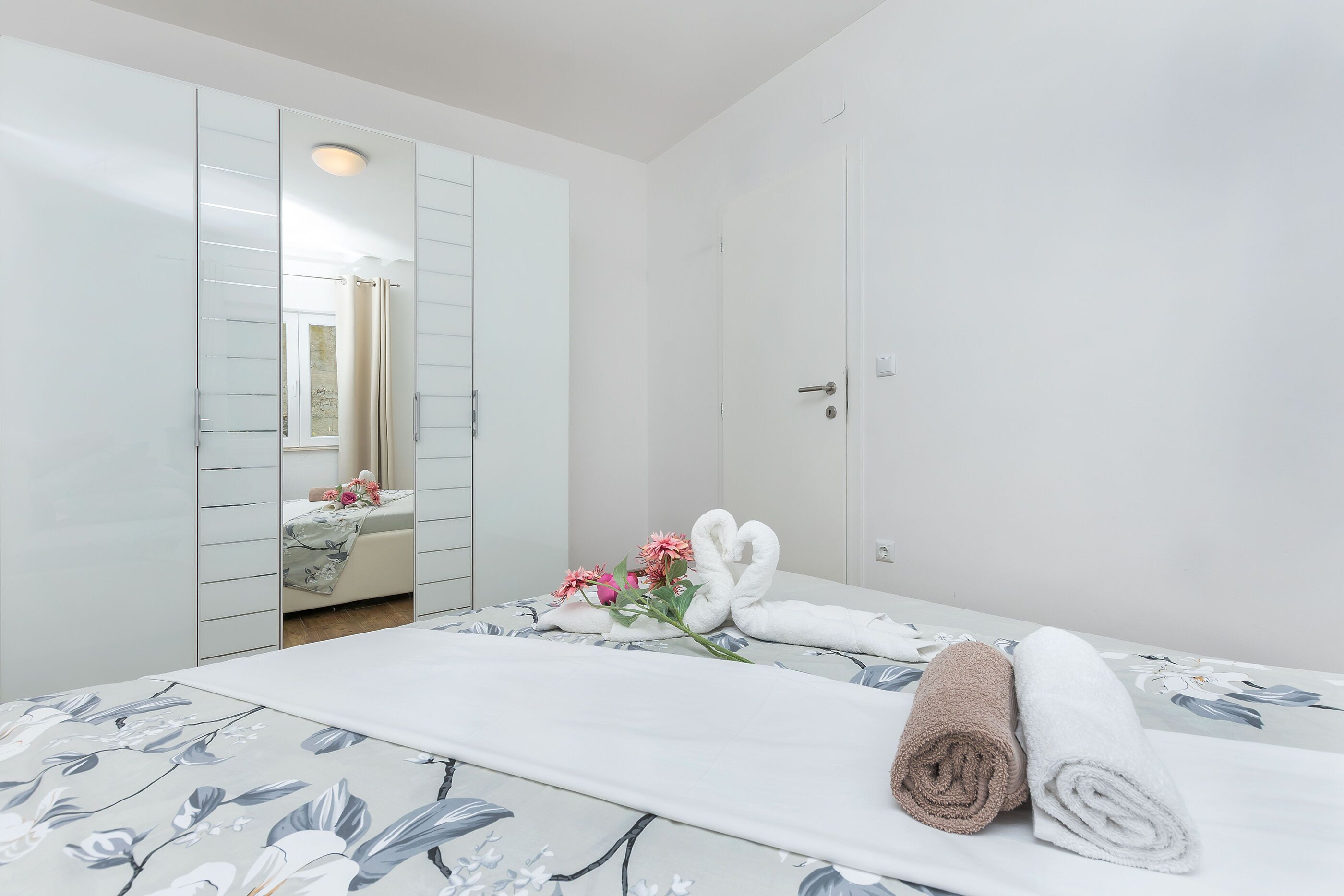 Een hotelkamer met een bed, een grote spiegel en een badkamer die door de spiegel zichtbaar is.