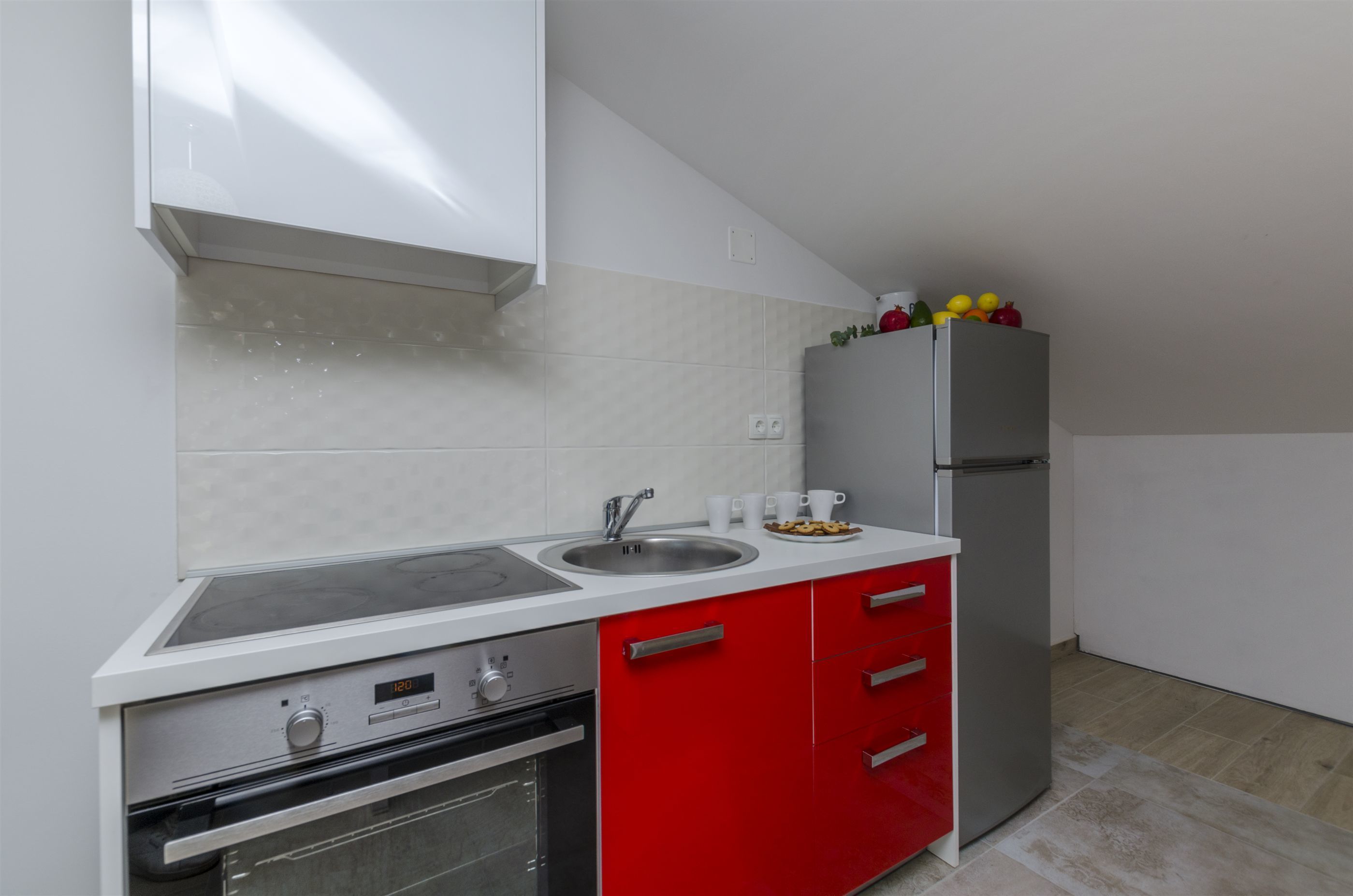 A compact kitchen with a stainless steel sink, a built-in oven, and a refrigerator.