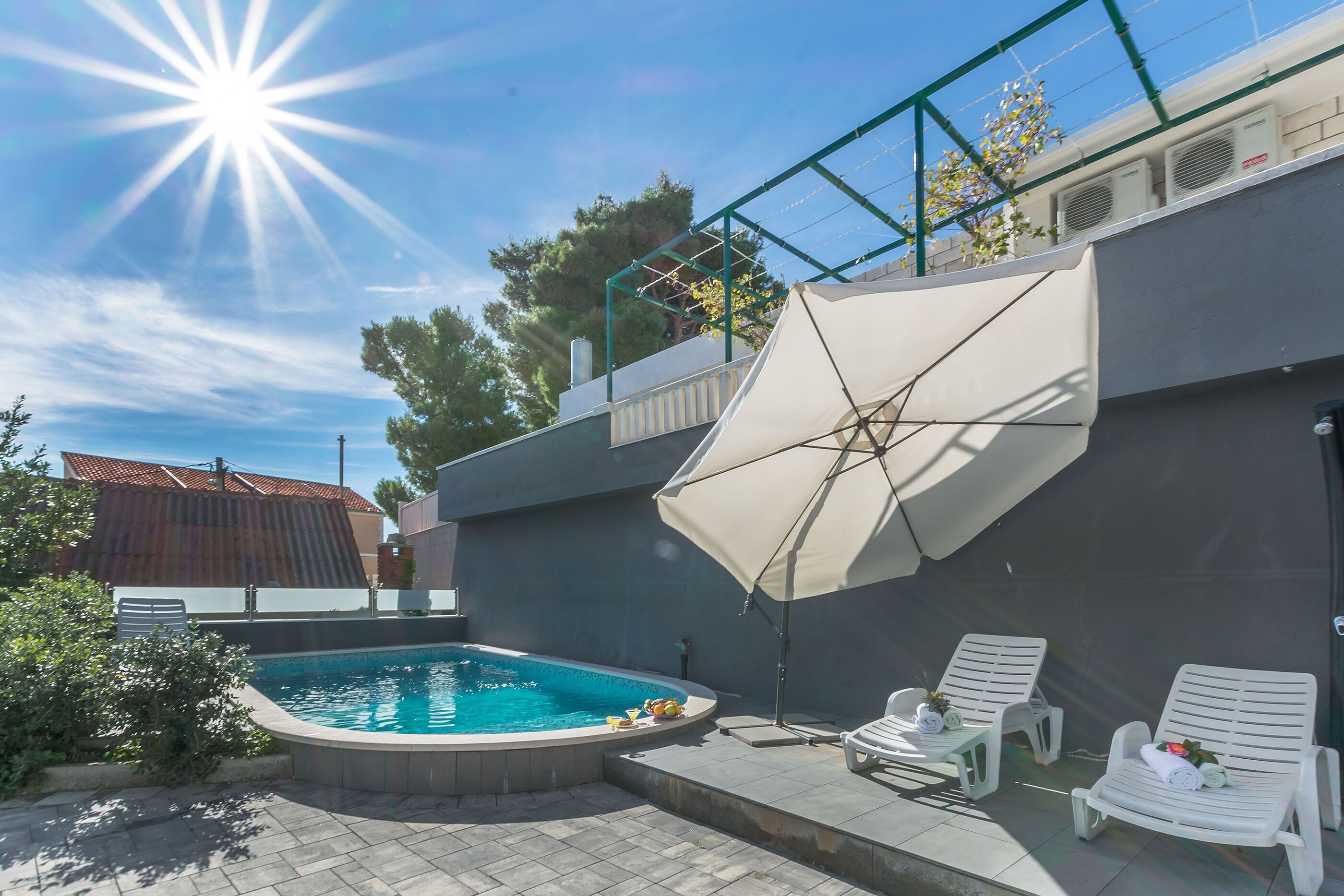 A swimming pool with lounge chairs and a sun umbrella.