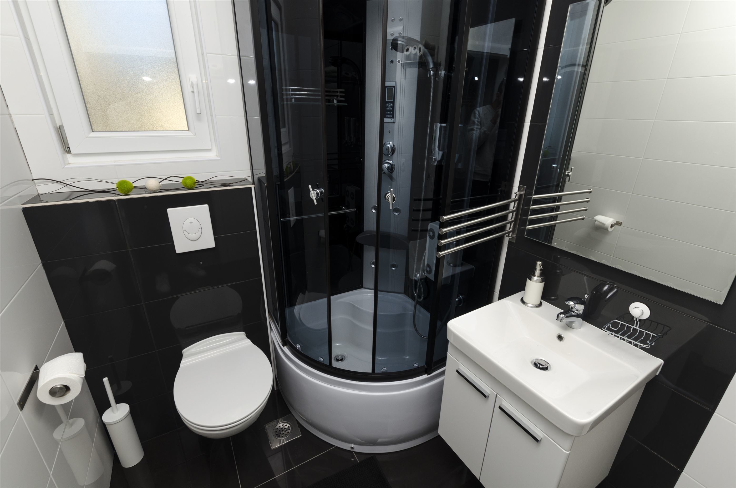 Ein modernes Badezimmer mit einer Duschkabine, einem weißen Waschbecken und einer Toilette.