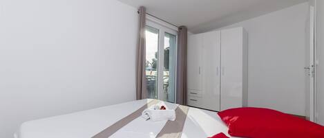 Een hotelkamer met een bed, een rood kussen, een witte handdoek en een schuifdeur naar een balkon.
