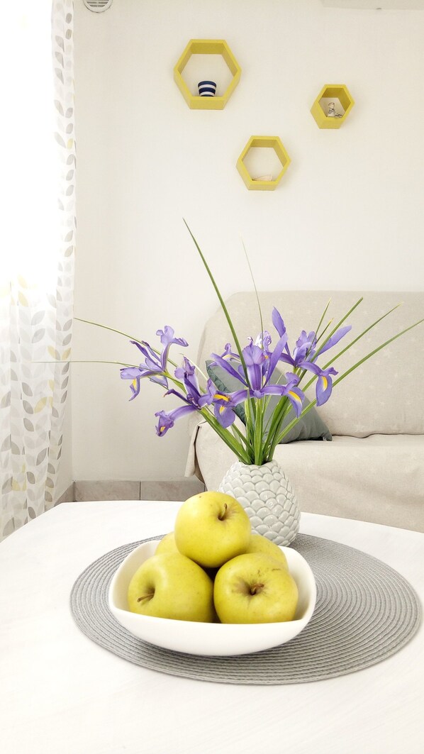 A white table with a bowl of green apples and a vase of purple flowers. - Apartments Franica (Vela Luka)