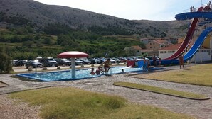 A swimming pool area with a water slide and a covered seating area. - Apartments Ena (Pag)