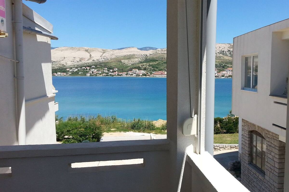 A balcony with a view of a coastal town and a large body of water.