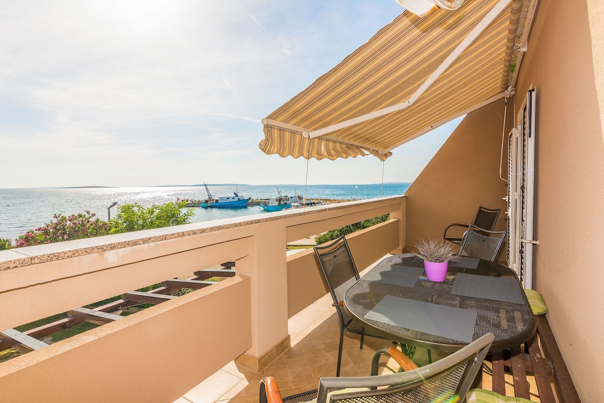 A balcony with a table, chairs, and a potted plant.