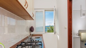 Cuina amb fogó de gas, un lavabo i una finestra amb persianes.