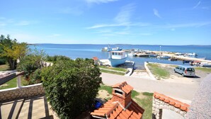 Un port esportiu amb embarcacions amarrades, un cel blau clar i una paret de pedra al primer pla.