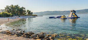 A beach with clear water, rocks, and inflatable water structures.