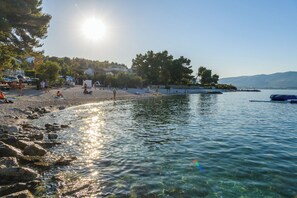 A beach with clear water, rocky shore, and a boat in the distance.
