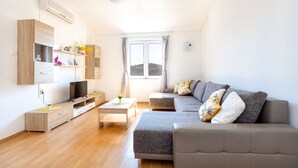 A modern living room with a sofa, TV, and built-in shelves. - Apartments Maja (Rogoznica)