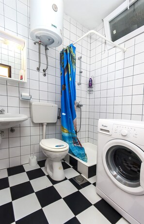 A bathroom with a toilet, a washing machine, a shower, and a sink. - Apartments Smilja (Tribunj)