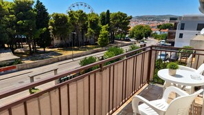 A balcony with a view of a road, trees, and a Ferris wheel.