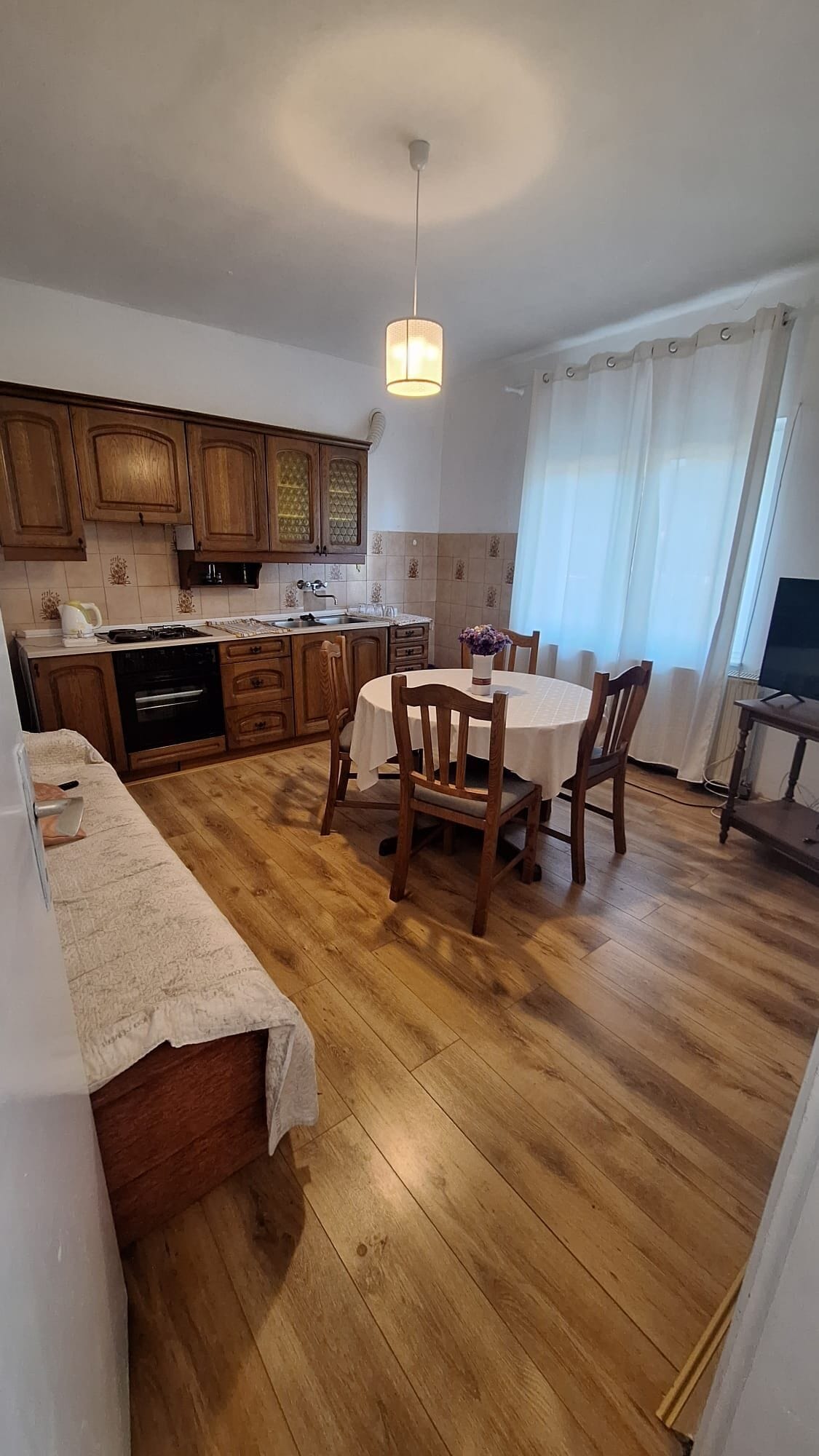 A kitchen with wooden cabinets, a dining table with chairs, and a hanging light fixture.
