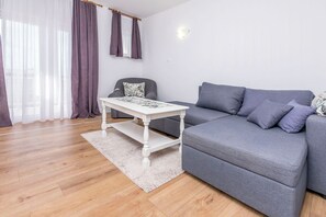 Ein modernes Wohnzimmer mit einem grauen Sofa, einem weißen Couchtisch und einem grauen Sessel.