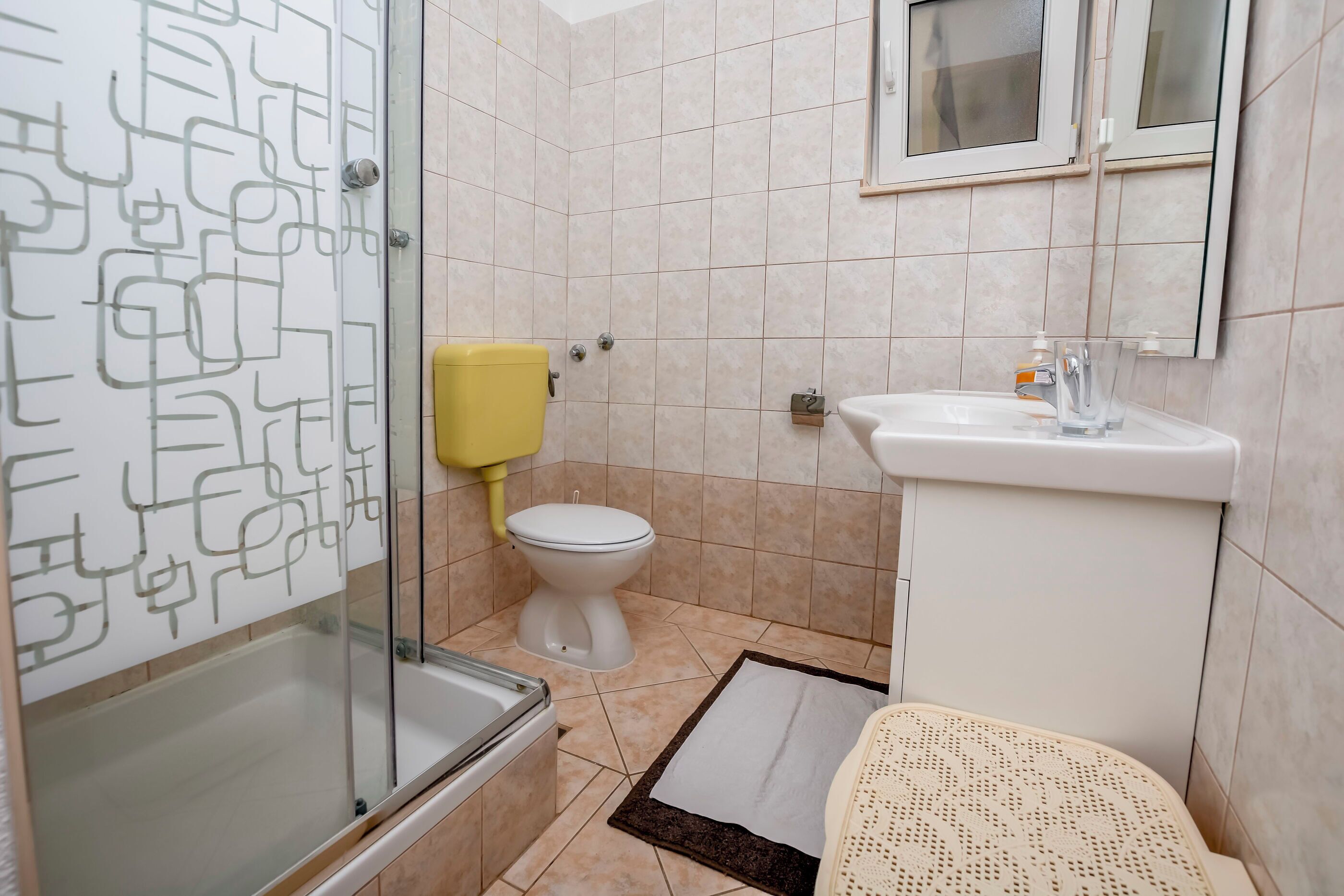 Une salle de bain avec une douche à parois de verre, des toilettes, un lavabo et un miroir au-dessus du lavabo.