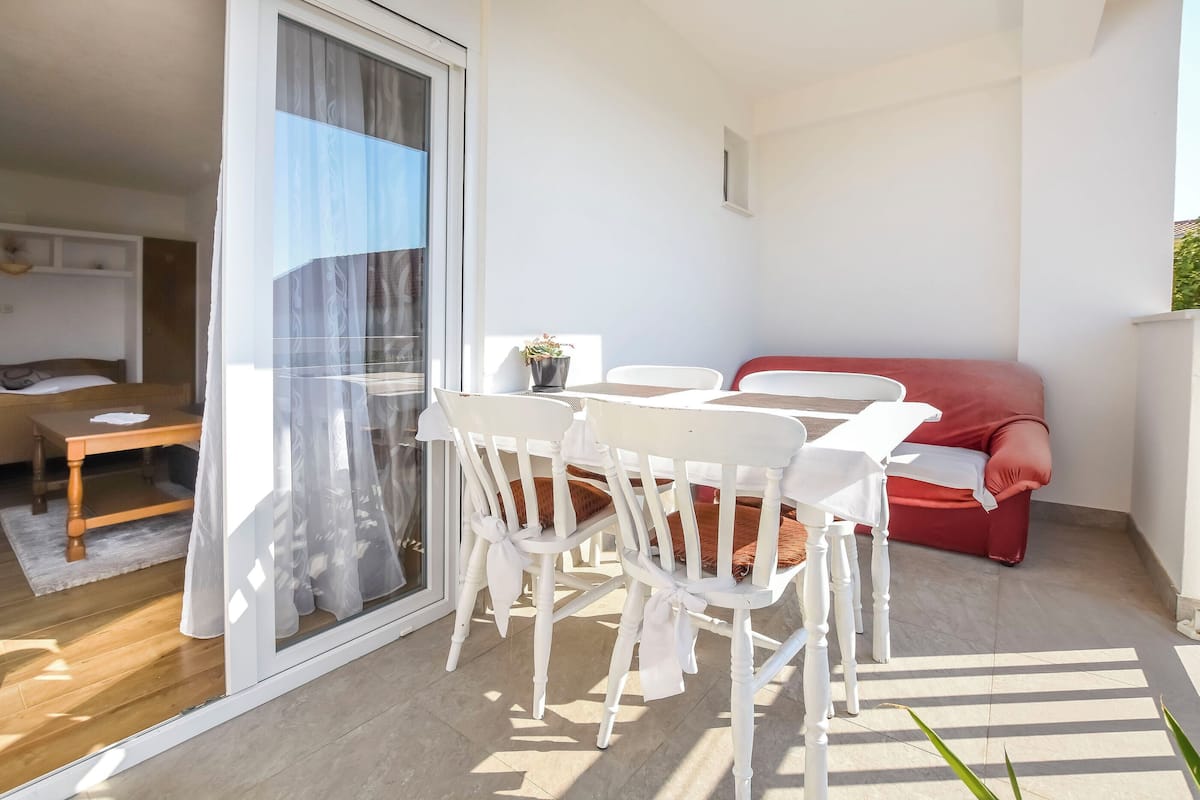 A balcony with a table and chairs, a red sofa, and a potted plant.
