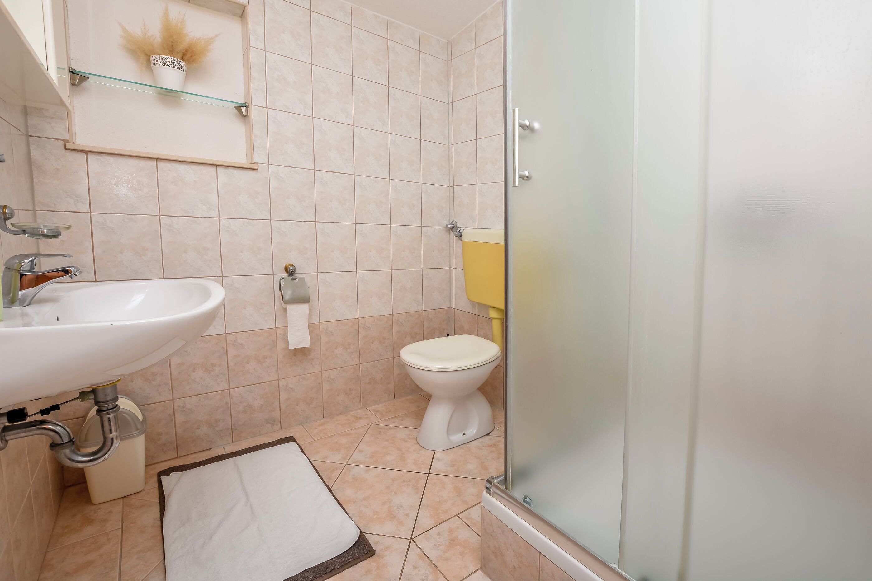 A bathroom with a sink, toilet, and glass shower enclosure.