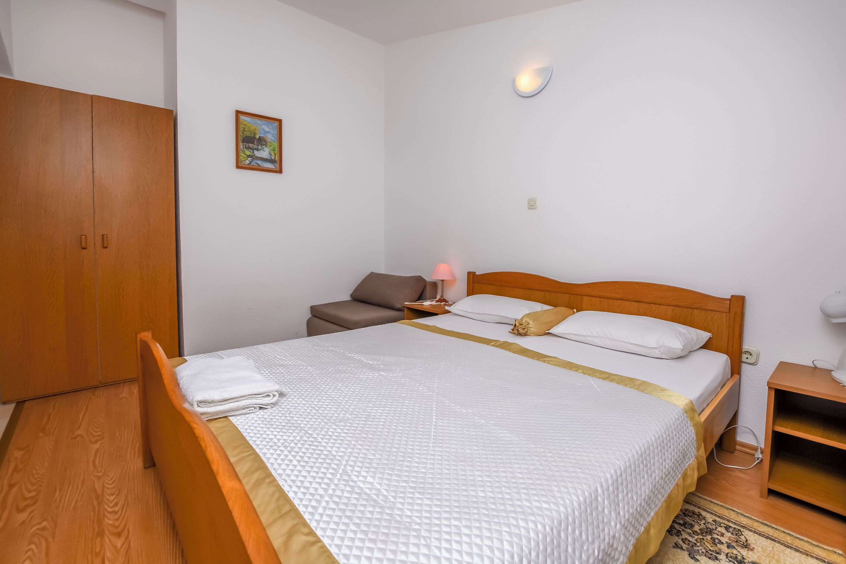 A neatly arranged bedroom with a bed, bedside table, lamp, and wardrobe.