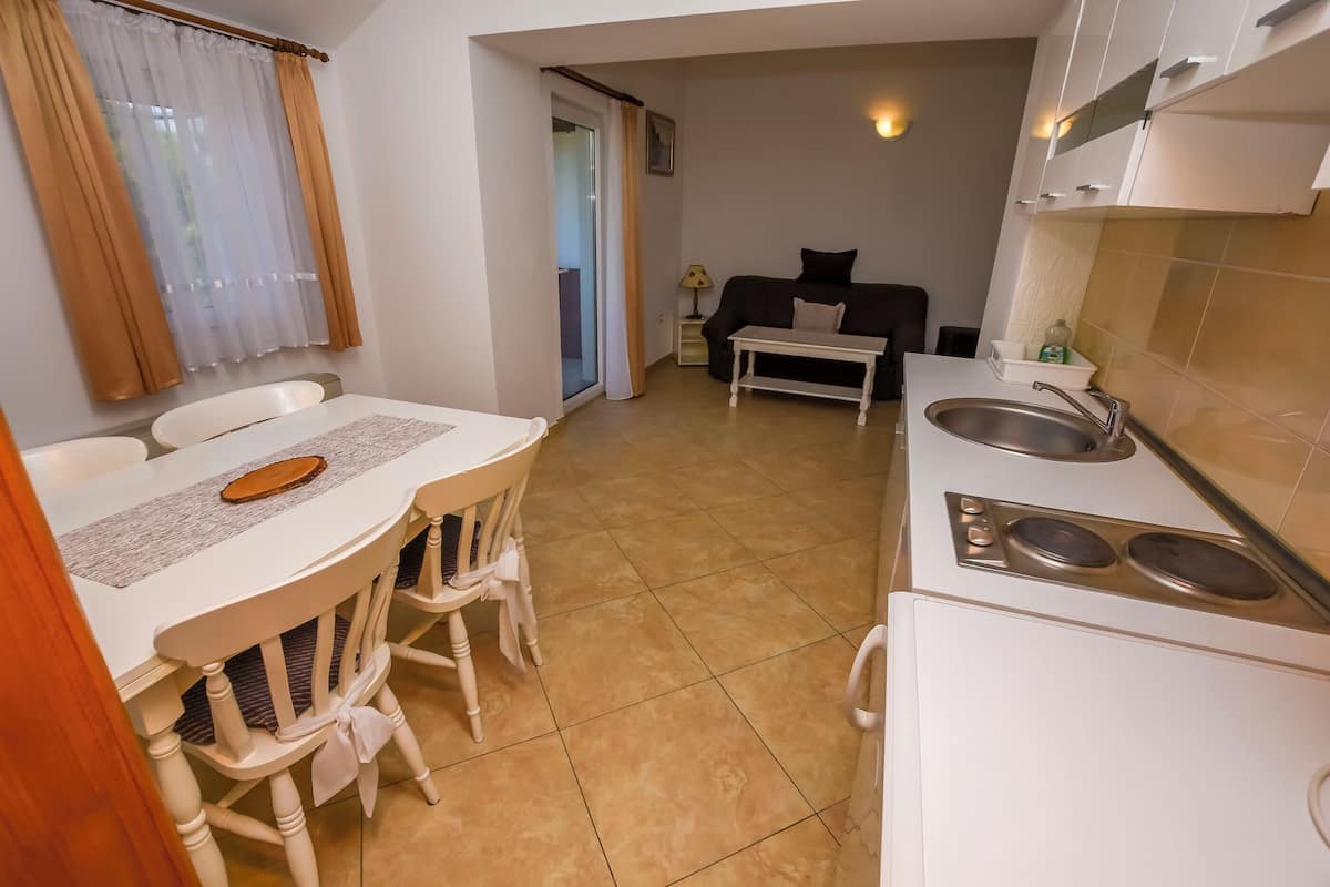 A compact kitchen with a dining area, a bed, and a small table.