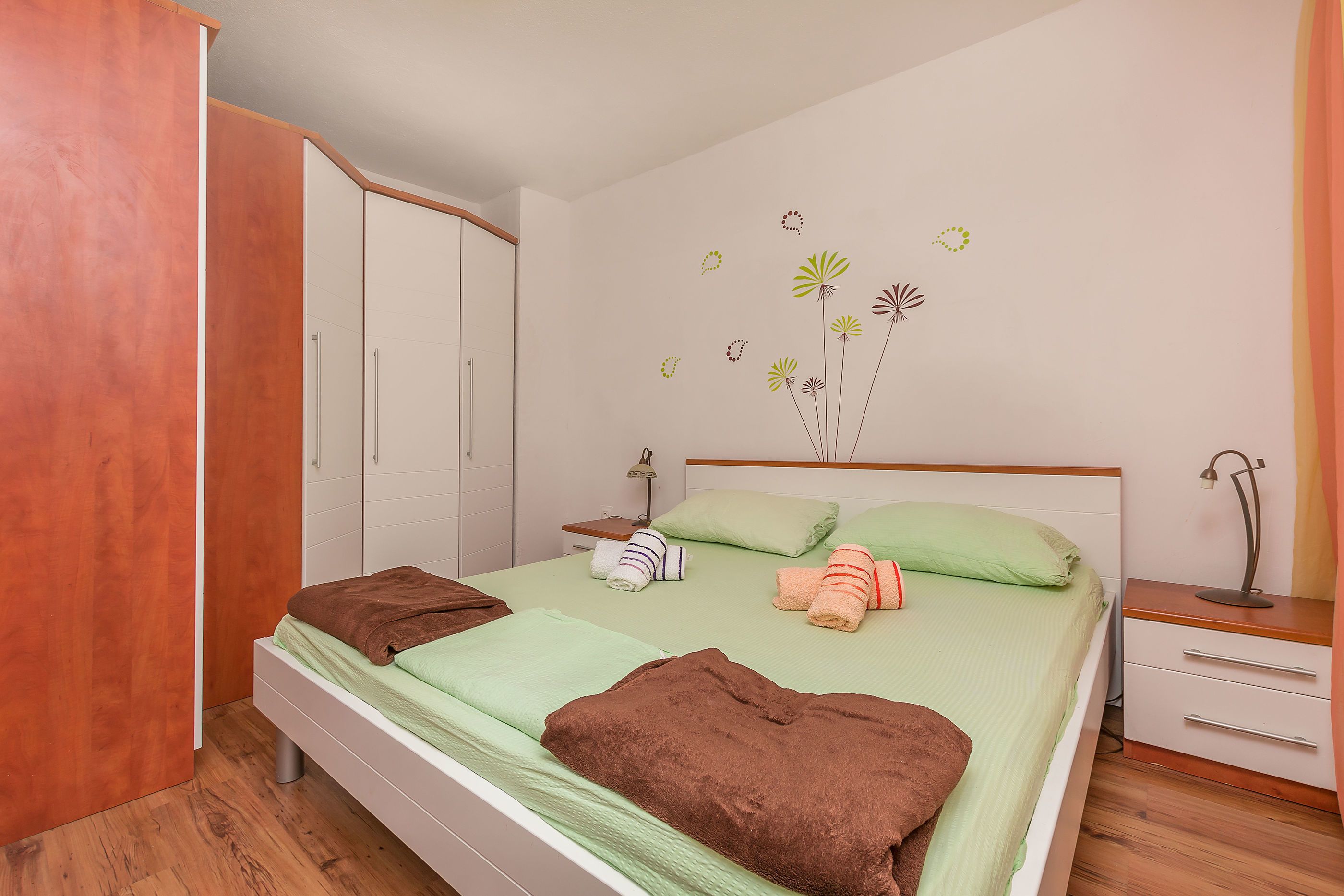 A bedroom with a bed, a wardrobe, a nightstand, and wall decorations.