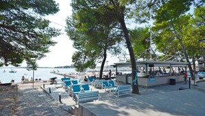 A waterfront promenade with seating areas, a boat dock, and a view of the sea. - Rooms Jeriko (Vodice)
